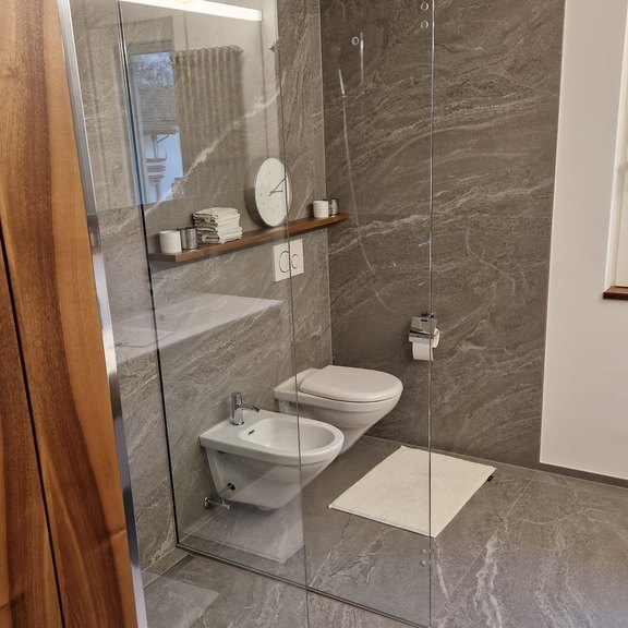 Fertiger Nassraum mit barriererfreier Dusche mit Verglasung und keramischen Grossformatplatten 120x120cm